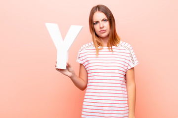 young pretty red head woman angry, anger, disagreement, holding the letter Y of the alphabet to...