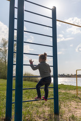A small child climbs the swedish wall outdoors