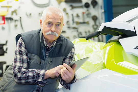 Senior Salesman Posing Next To Jet Ski In His Store