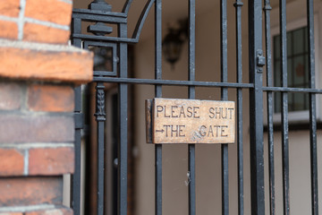 Wooden Sign on a Metal Gate: Please Shut the Gate