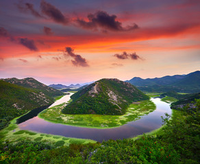 A curvy stretch of Rijeka Crnojevica, Montenegro, Europe. Amazing dramatic sunset (sunrise) view of Skadar lake national park, Pavlova Strana. Viewpoint Ridge mountains panoramaic landscape. .
