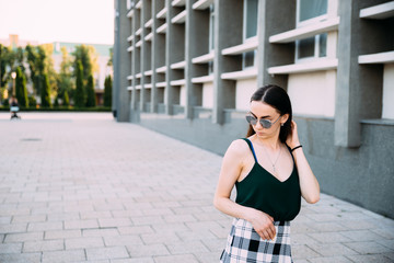 Sexy girl in a T-shirt, sunglasses and mini shorts near the wall