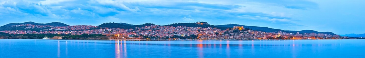 Fototapeta na wymiar Large panorama of Unesco heritage historic town of Sibenik on Adriatic sea, Dalmatia, Croatia. Shot from the sea, harbor, waterfront and cathedral in front and ancient fort overlooking the town on.