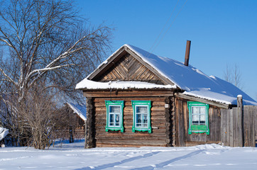Winter landscape on a Sunny day. View of the Russian village in the snow. Authentic Wooden houses with carved frames.