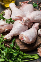Raw uncooked chicken legs with spices and ingredients for cooking on cutting board