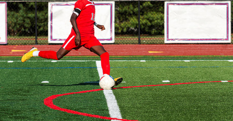 Soccer player in red uniform about to kick the ball
