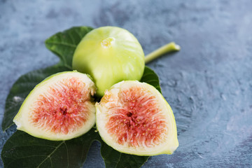 Ripe sweet green figs with green leaves. Healthy mediterranean fig fruit on a blue wooden...