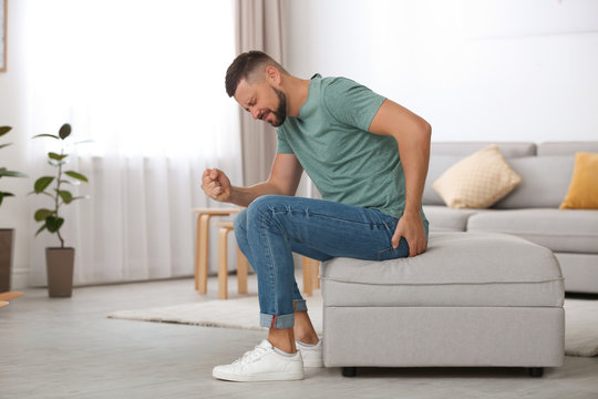 Man suffering from hemorrhoid in living room