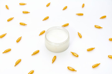 Top view on a jar of white cream and gold capsules with collagen on a white background. The concept of beauty, facial skin care, cosmetology, medicine