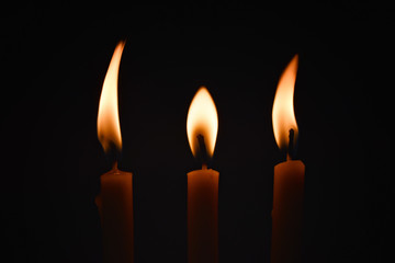 Three candles with waxed wax and dancing lights on a black background