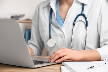 Doctor working with laptop at desk in office, closeup. Medical service