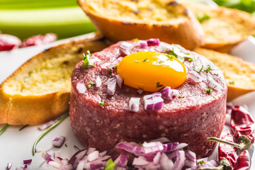 Beef tartare with egg yolk red onion chili peppers herbs and bruschetta