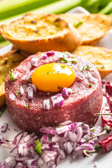 Beef tartare with egg yolk red onion chili peppers herbs and bruschetta