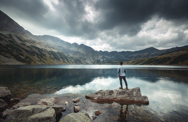 A man stands on a rock on the lake. Mountain view. Valley of Five Ponds in the Tatra mountains.