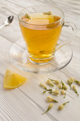 Jasmine green tea in the glass cup on the white wooden background. Location vertical.