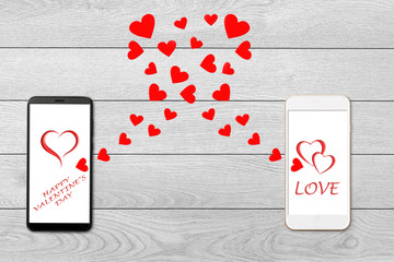 Valentine day concept, love message - hearts flying out of two smartphone, Isolated on white wooden background