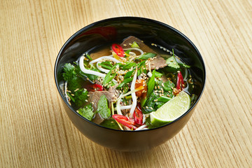Close up view on tasty, traditional pho Vietnamese soup consisting of broth, rice noodles, herbs, and meat - beef. Street-food