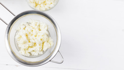 Homemade fermented beverage kefir with kefir grains in bowl on a white background, concept of natural fermented food and gut health