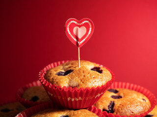 Muffins with blueberries and raspberries. Cupcakes with Valentine's Day decor. Flat lay. Banner. On a red background