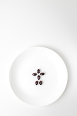 Astaxanthin pills form a human shape on the white plate.