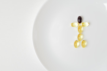 Fish oil and astaxanthin capsules on a plate in a human shape.