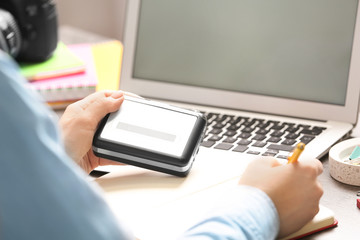 Journalist with voice recorder working at table in office, closeup