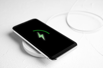 Mobile phone charging with wireless pad on white stone table © New Africa