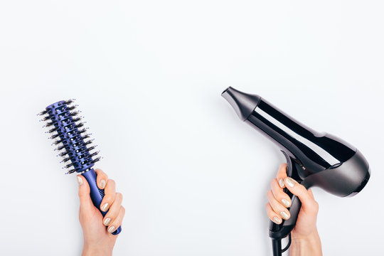 Female Hands Holding Hair Dryer And Hairbrush