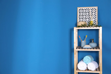 Shelving unit with toiletries near blue wall indoors, space for text. Bathroom interior element