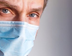Close up headshot of  person wearing a surgical face mask as protection against transmission