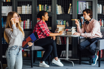 People, knowledge, education and school concept - happy blonde woman with book in library.