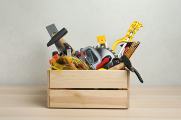 Crate with different carpenter's tools on wooden table