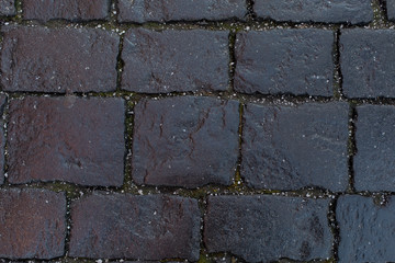 Black stones of an old pavement. Backdrop background texture, square rectangular geometric cobblestones, ice crumb