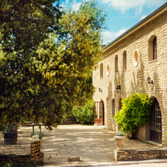 Fototapeta na wymiar Beautiful old stone provencal chateau vineyard in sunny summer day with stone yard and garden around in heart of Provence. Provence tourist destination. Best vacation ever