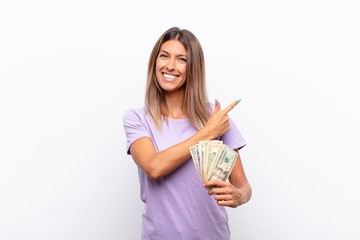 young pretty woman looking arrogant, successful, positive and proud, pointing to self with banknotes
