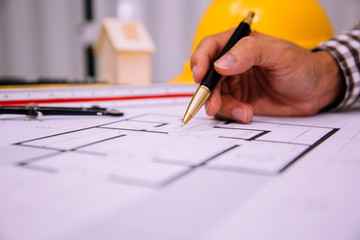 Close-up hand of male Architect drawing blueprint on work space in construction site.