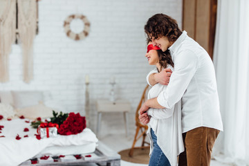 man embracing girlfriend in blindfold on the eyes making surprise for st valentines day