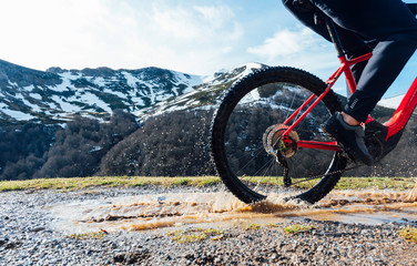 Man riding a mountain bike passing a puddle of water