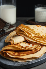 Fresh thin pancakes on grey board, closeup