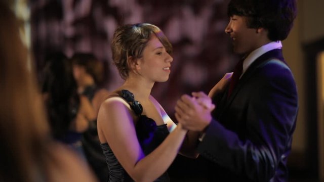 A teenage boy and girl dancing at a senior prom high school dance