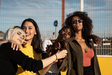 Cheerful young diverse female friends celebrating meeting in city