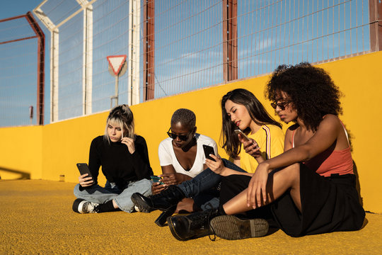 Carefree young multiracial female friends using smartphone in stadium