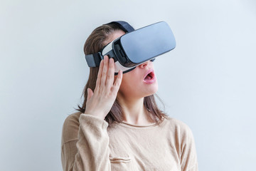 Smile young woman wearing using virtual reality VR glasses helmet headset on white background. Smartphone using with virtual reality goggles. Technology, simulation, hi-tech, videogame concept.