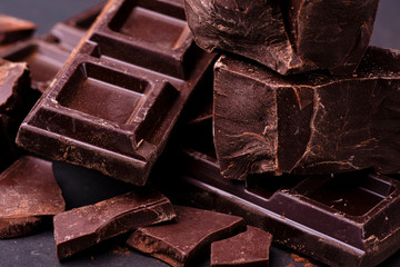 in the foreground stacked pieces of dark chocolate sprinkled with cocoa powder.