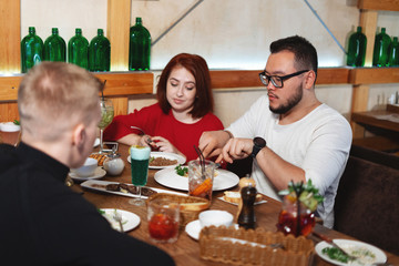 Friends in their having a nice lunch on wooden table in a cafe.