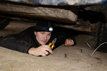a man under the car, fixing the car, pumping the brakes