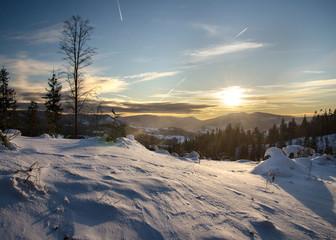 Winter mountain landscape in the Carpathians with sunrays reflecting in the snow near sunset and beautiful coniferous forest, Krawcow Wierch trail, Beskid Zywiecki, Poland