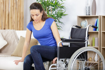 disabled woman in wheelchair trying to sit on sofa