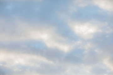 A light blue sky on an overcast day with big fluffy clouds scattered across the skyline