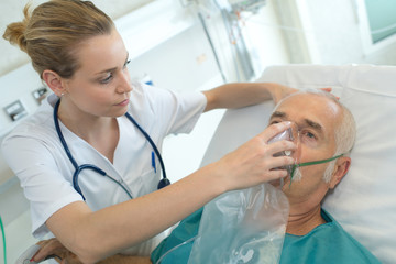 female doctor applying oxygen mask on senior patient